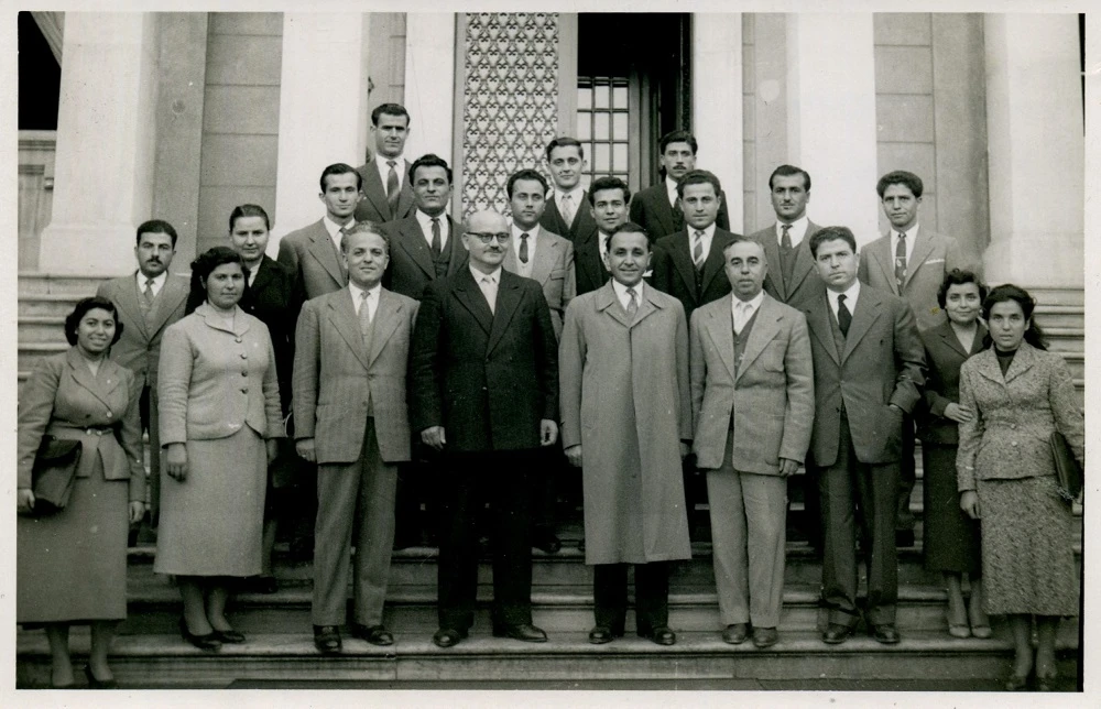 Καθηγητές και φοιτητές της Θεολογικής Σχολής του ΑΠΘ στην είσοδο του «παλαιού κτιρίου». Από δεξιά, Σάββας Αγουρίδης, Δημήτριος Μωραΐτης, Μάρκος Σιώτης, Βασίλειος Έξαρχος, ΙΟΚ. Η πίσω όψη με ιδιόχειρη σημείωση του ΙΟΚ «Νοέμβριος 1956» και ιδιόχειρη σημείωση του Γεωργίου Στογιόγλου ως επικ. καθ. της Θεολογικής Σχολής πολύ αργότερα, στην οποία κάνει ταυτοποίηση των εικονιζόμενων καθηγητών. Φωτογραφία από το προσωπικό αρχείο του καθηγητή του ΑΠΘ Ιωάννη Καλογήρου, το οποίο έχει παραχωρηθεί στην Κοσμητεία της Θεολογικής Σχολής του ΑΠΘ για τις εκδηλώσεις εορτασμού των 80 χρόνων της Θεολογικής Σχολής.