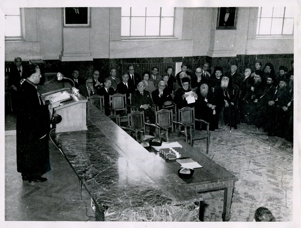 Από την αναγόρευση των «πέντε» σε επίτιμους διδάκτορες της Θεολογικής Σχολής, 13 Νοεμβρίου 1959. Τη laudatio και για τους πέντε, εκφώνησε ο ΙΟΚ.Οι τιμώμενοι από δεξιά: ο Μητροπολίτης Θεσσαλονίκης Παντελεήμων Α’, ο Επίσκοπος Κατάνης Κασσιανός, πρύτανης τότε του Ορθοδόξου Θεολογικού Ινστιτούτου στο Παρίσι, ο Αιδεσιμώτατος Πρωτοπρεσβύτερος Γεώργιος Φλωρόφσκυ και οι Αμίλκας Αλιβιζάτος και Γεώργιος Σωτηρίου, ομότιμοι καθηγητές της Θεολογικής Σχολής Αθηνών. Ανάμεσα από τους δύο τελευταίους, σε δεύτερο πλάνο η σύζυγος του ΙΟΚ, Μαίρη Καλογήρου. Στο βήμα ο ΙΟΚ εκφωνεί τη laudatio.Η πίσω όψη με ιδιόχειρη αφιέρωση του Παντελεήμονα Α’ στον ΙΟΚ: «Τω φιλτάτω μοι Καθηγητή Κω Ιωάννη Καλογήρου μετά πολλής αγάπης, θερμών ευχαριστιών και εγκαρδίων ευχών, εις ανάμνησιν ο Θεσσαλονίκης Παντελεήμων 13-11-1959».Φωτογραφία από το προσωπικό αρχείο του καθηγητή του ΑΠΘ Ιωάννη Καλογήρου, το οποίο έχει παραχωρηθεί στην Κοσμητεία της Θεολογικής Σχολής του ΑΠΘ για τις εκδηλώσεις εορτασμού των 80 χρόνων της Θεολογικής Σχολής.