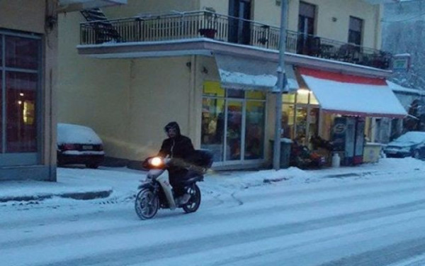 Διανομείς παίρνουν το μηχανάκι στα χέρια για να παραδώσουν την παραγγελία μέσα στο χιόνι