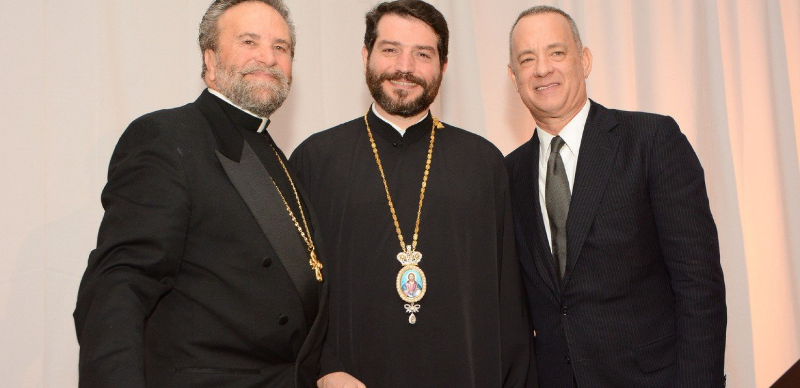 Ο π. Ιωάννης Μπάκας με τον Επίσκοπο Μηδείας κ. Απόστολο και τον ηθοποιό Τομ Χάνκς, σύζυγο της ομογενούς Ρίτα Ουίλσον, που έχει ασπαστεί την Ορθοδοξία. Φωτογραφία: Allen Altchech Photography
